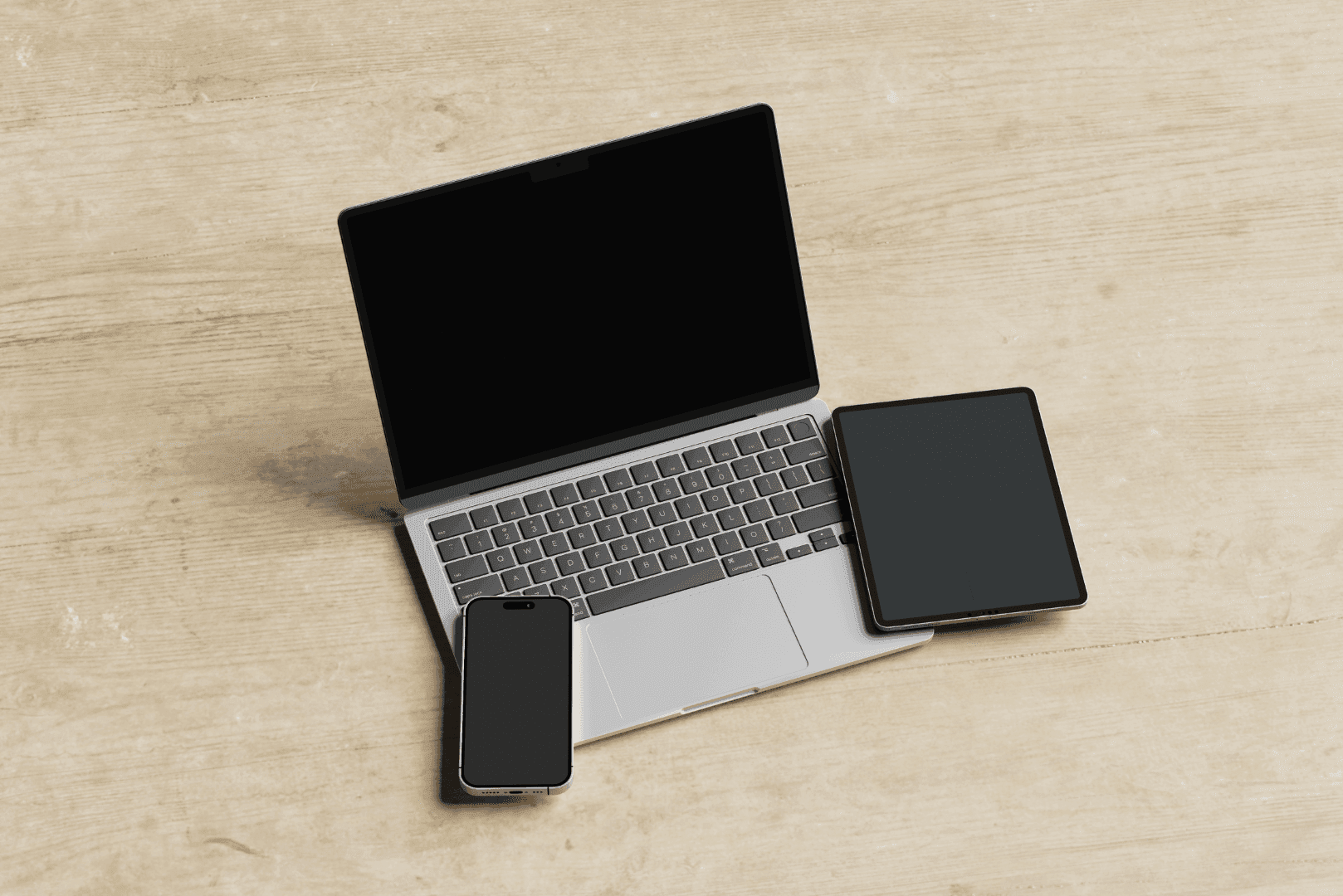 Zestawienie trzech urządzeń: otwartego laptopa, tabletu oraz smartfona na drewnianym blacie – symbol pełnej responsywności witryny.