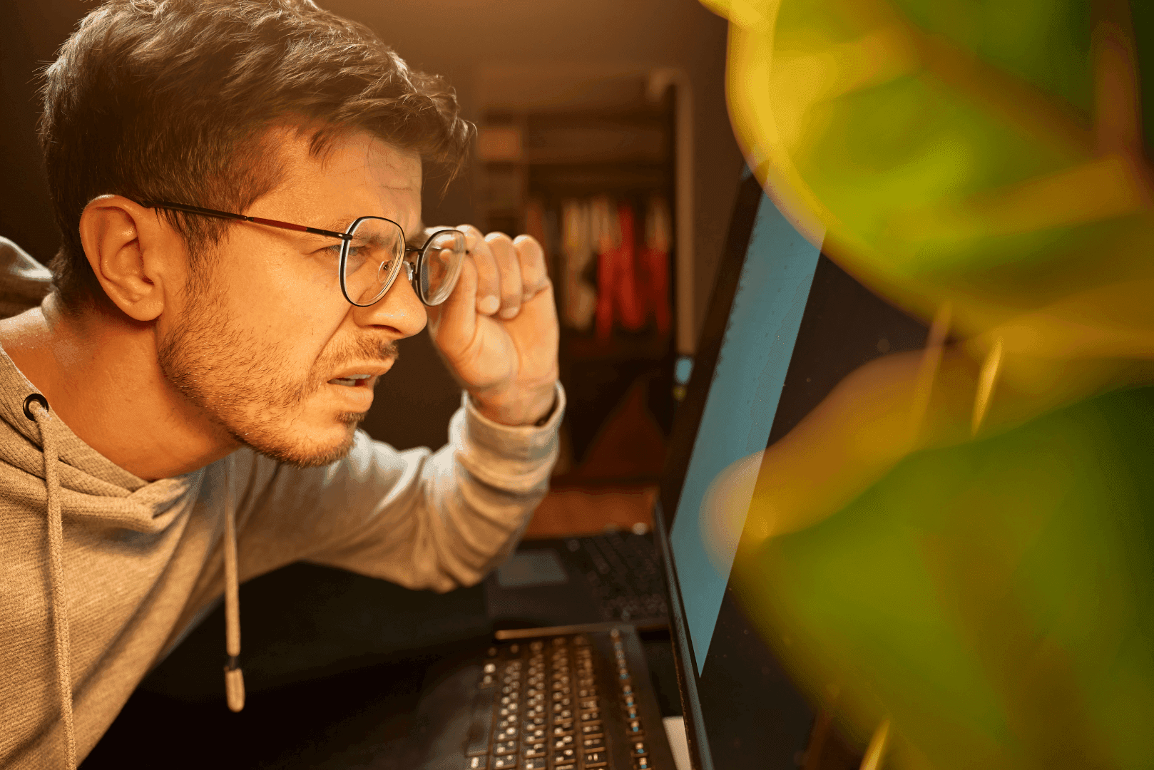 Mężczyzna w okularach z grymasem frustracji patrzący z bliska w monitor komputera – symbol spadku zaufania klientów do niestabilnej strony.