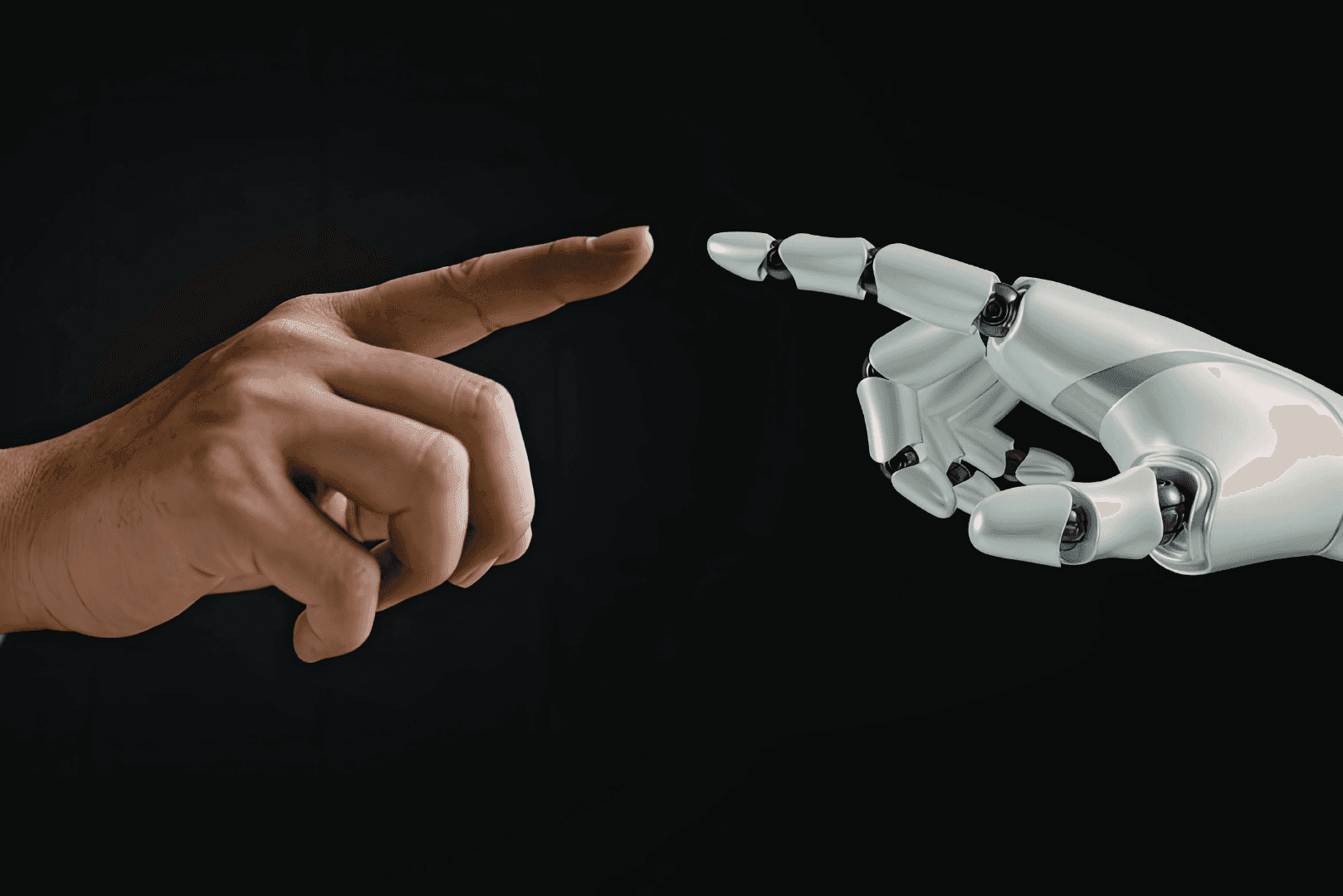 Zbliżenie na ludzki palec wskazujący zbliżający się do palca białej, robotycznej dłoni na czarnym tle – symbol automatyzacji.